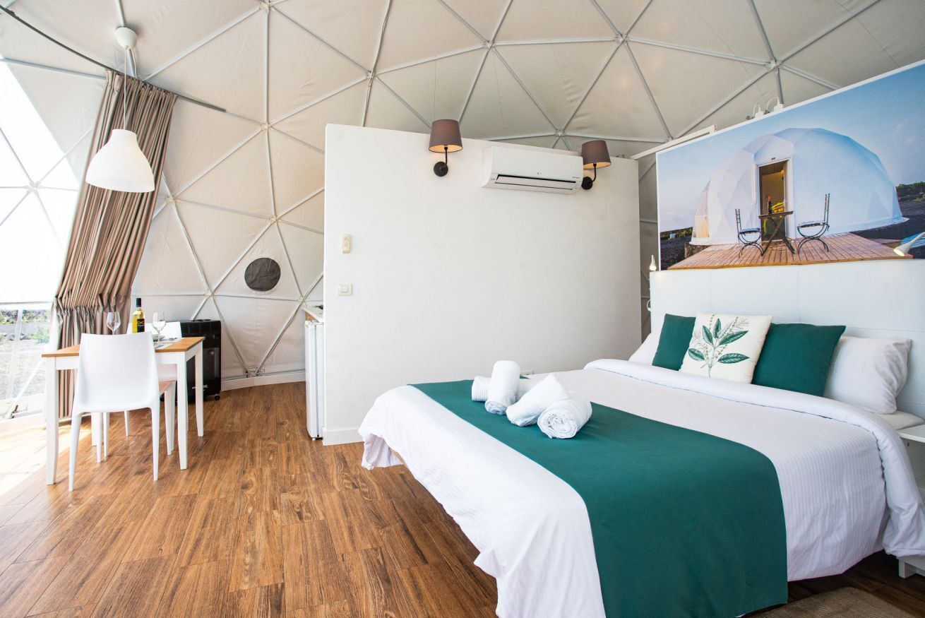 Een moderne kamer met een groot bed, een eethoek en uitzicht op een koepelstructuur.