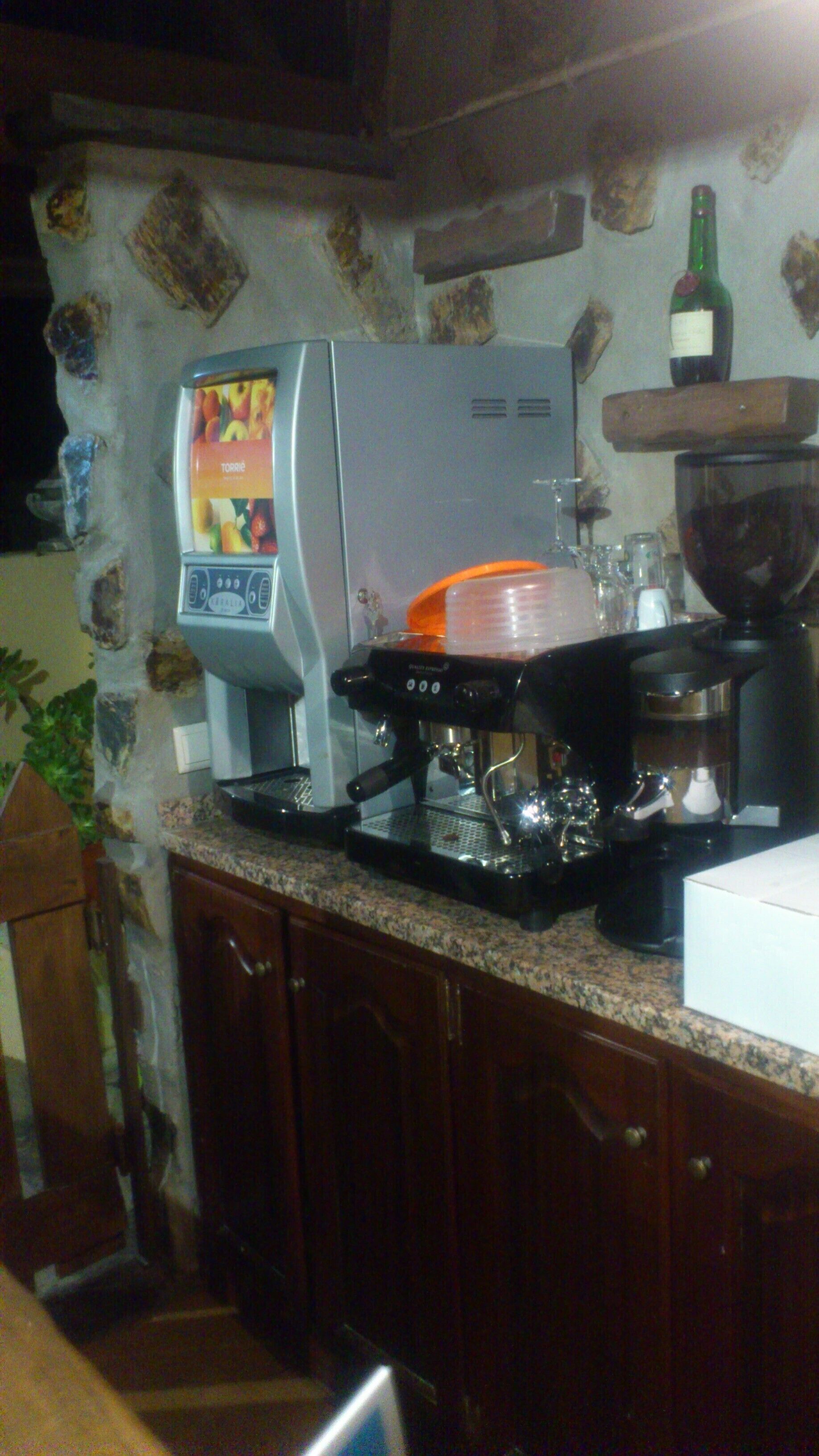 Une cuisine équipée d’une machine à café, d’un réfrigérateur et d’une bouteille de vin posée sur le comptoir.