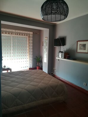 A bedroom with a bed, a potted plant, a television, and a wall-mounted shelf. - Portfólio Guesthouse (Porto)