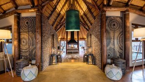 A spacious lobby with a high ceiling, patterned walls, and a central seating area. - Hoodia Desert Lodge (Sesriem)