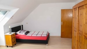 A bedroom with a bed, a nightstand, a wardrobe, and a skylight. - Monteurzimmer & FeWo G. Klement Aurach (Herrieden)