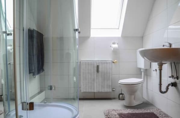 A modern bathroom with a glass shower enclosure, a white toilet, and a sink with a wooden basin. - Monteurzimmer & FeWo G. Klement Aurach (Herrieden)