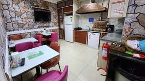 Un restaurante con paredes de piedra, televisión, área de cocina y extintor.