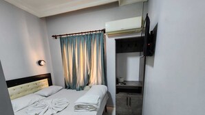 Habitación de hotel con cama, televisor montado en la pared, armario y baño con inodoro y perchero.