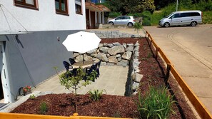 A patio with a table and chairs, a white umbrella, and a stone wall.