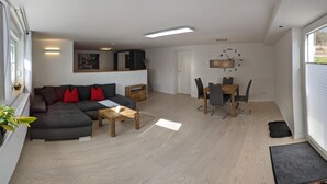 A modern living room with a sofa, coffee table, and dining area with chairs and a table. - Apartment in a very quiet location, 12 km to Europa Park Rust (Herbolzheim)