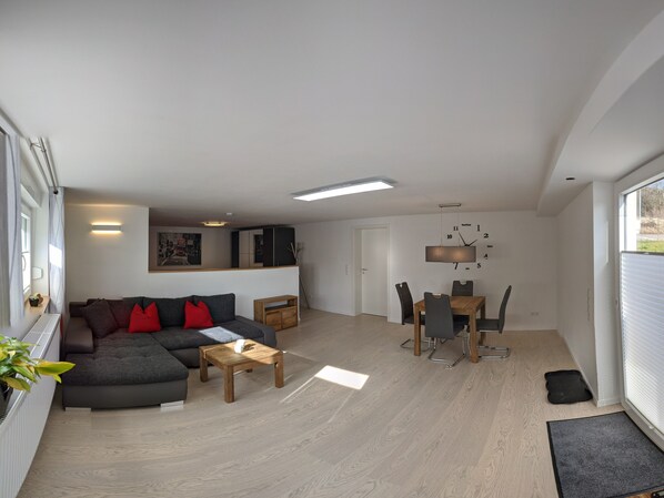 A modern living room with a sofa, coffee table, and dining area with chairs and a table.