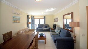 Ein Wohnzimmer mit einem Holzesstisch, zwei Sofas, einem Fernseher und einer Lampe.