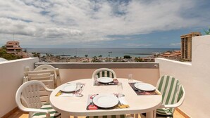 A balcony with a table set for two, overlooking a coastal cityscape. - Azahara Playa 23 - Studio (Arona)
