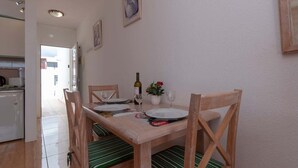 A dining area with a wooden table set for two, a bottle of wine, and a potted plant. - Azahara Playa 23 - Studio (Arona)