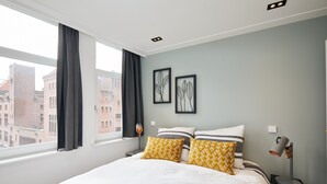 Habitació d'hotel amb un llit gran, dos almoinos decorats, una làmpada de nit i obra d'art emmarcada a la paret.