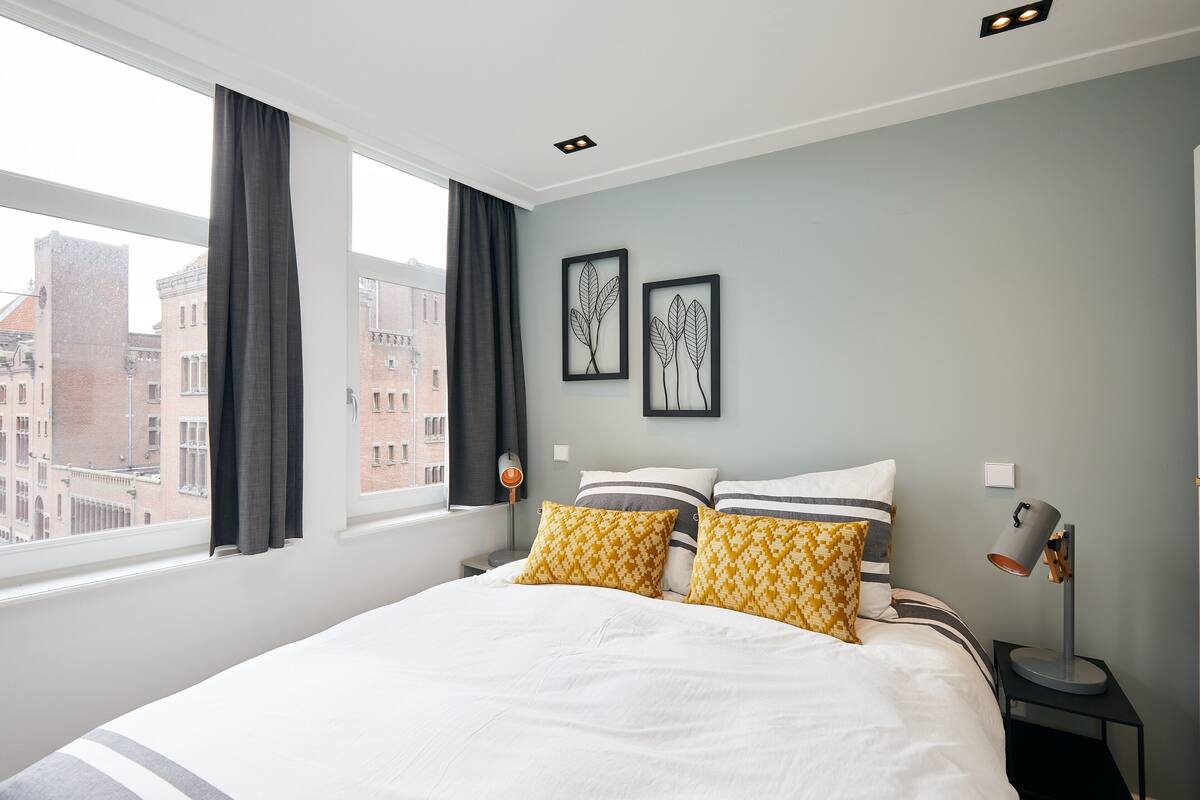 A hotel room with a large bed, two patterned pillows, a bedside lamp, and framed artwork on the wall.