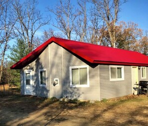 A single-story house with a red roof, a front door, and two windows.