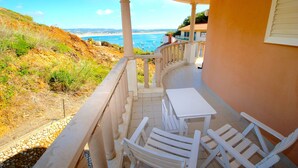 A balcony with white furniture, a view of the sea, and a building with a red roof. - Lighthouse - 3 story holiday home with shared tennis court and sea views (São Martinho do Porto)