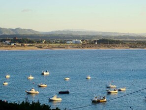 A coastal scene with multiple boats on calm water, a sandy beach, and a distant shoreline with buildings and hills. - Lighthouse - 3 story holiday home with shared tennis court and sea views (São Martinho do Porto)
