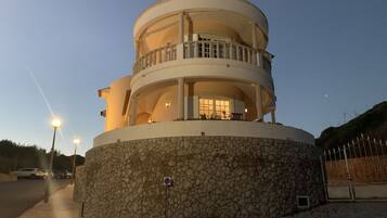 A multi-level, circular building with balconies and a stone base.