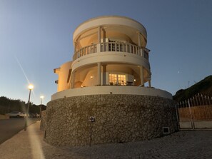 A multi-level, circular building with balconies and a stone base. - Lighthouse - 3 story holiday home with shared tennis court and sea views (São Martinho do Porto)