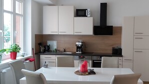 Eine moderne Küche mit weißen Schränken, einer Mikrowelle, einer Kaffeemaschine und einem Essbereich mit Tisch und Stühlen.