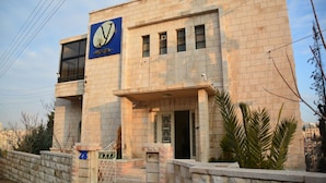 A hotel with a prominent sign, a gated entrance, and a stone facade. - The Y Hotel Amman (Amman)