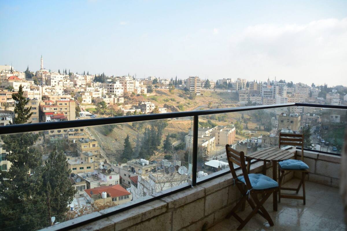 Un balcon offrant une vue sur le paysage urbain, avec des bâtiments et une mosquée.