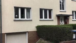 A multi-story residential building with multiple windows, a garage door, and a small garden area. - Fewo Reißhausstraße 23 - 2 Schlafzimmer (Erfurt)