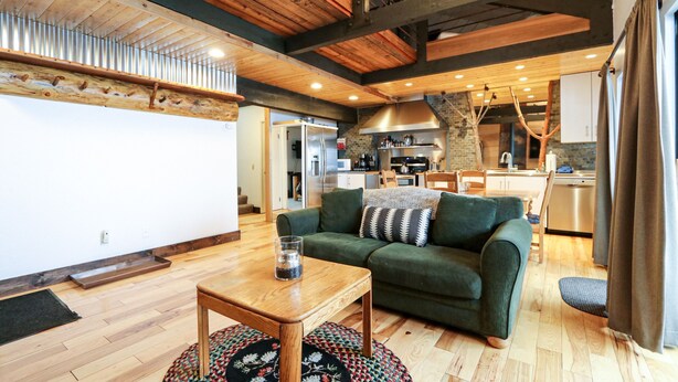 A modern living room with a wooden ceiling, a green sofa, a wooden coffee table, and a kitchen in the background. - Bigwood 80 Remodeled, Private Washer Dryer, Close to Eagle Lodge by RedAwning (Mammoth Lakes)