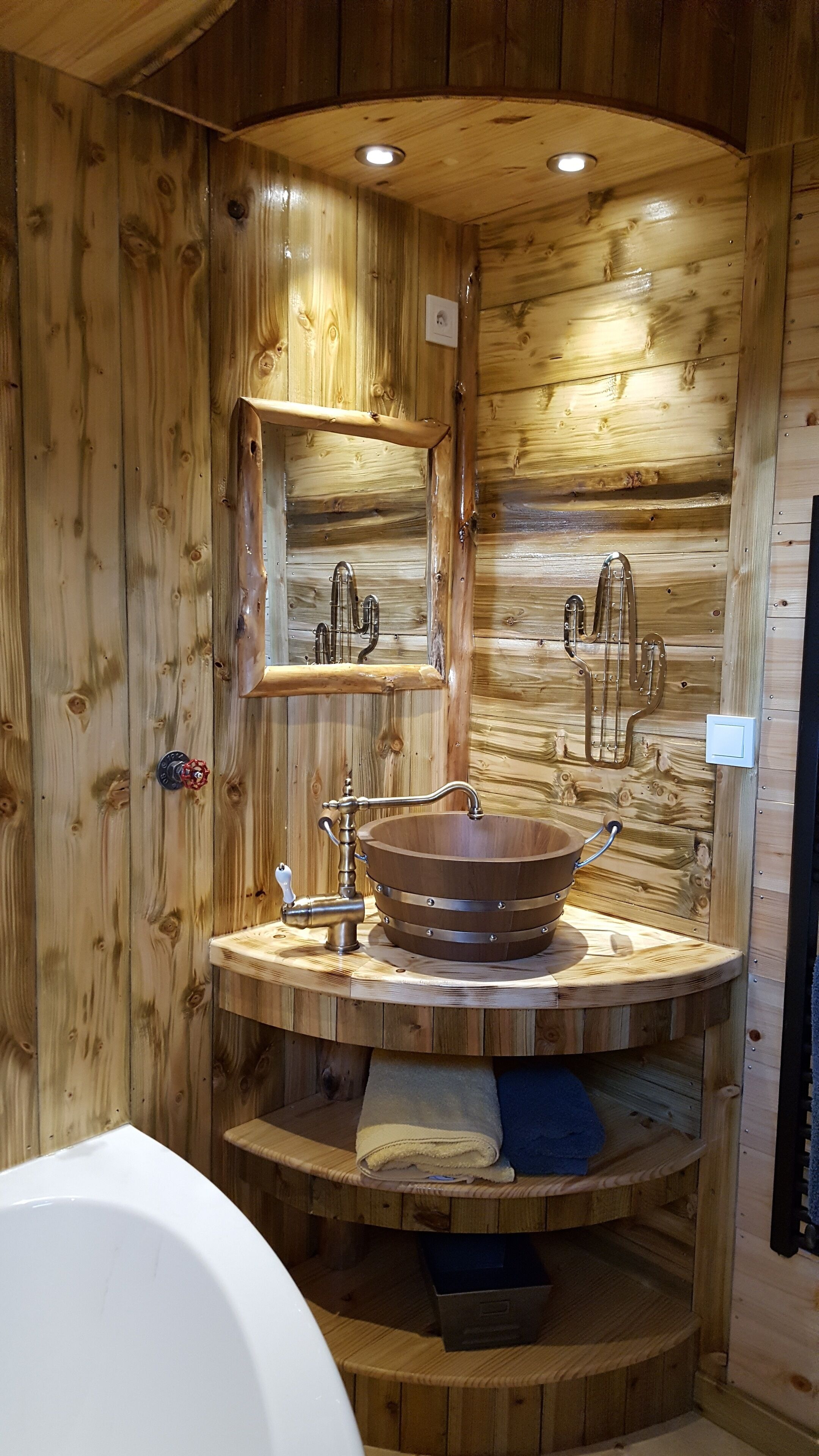 A wooden cabin bathroom with a wooden sink, a mirror, and a towel rack.