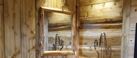 A wooden cabin bathroom with a wooden sink, a mirror, and a towel rack.