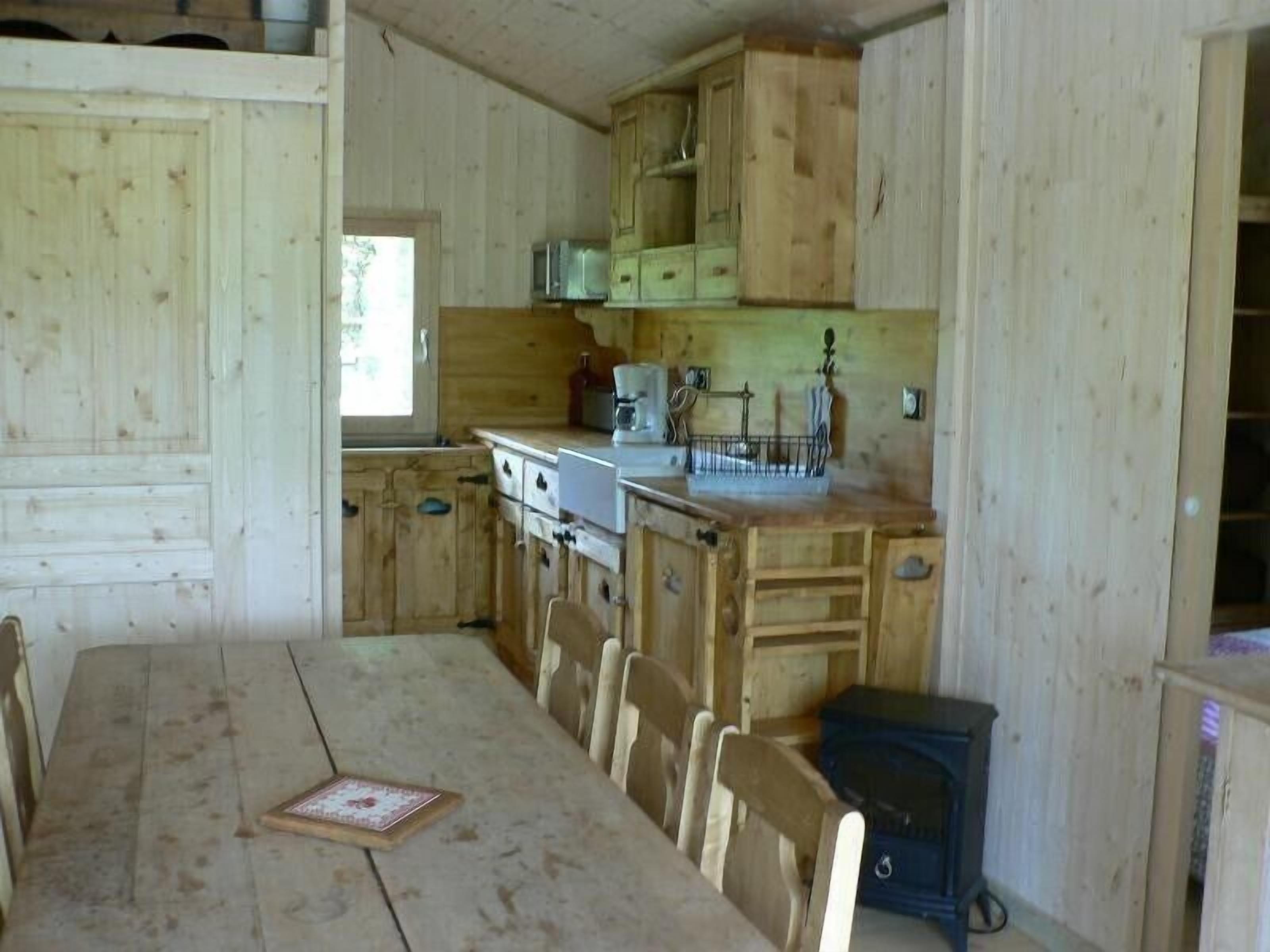 Una cocina rústica de madera con una mesa de comedor, sillas y un estufa de leña.