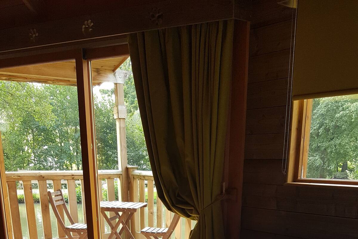 A room with a bed, a window, and a view of an outdoor deck.