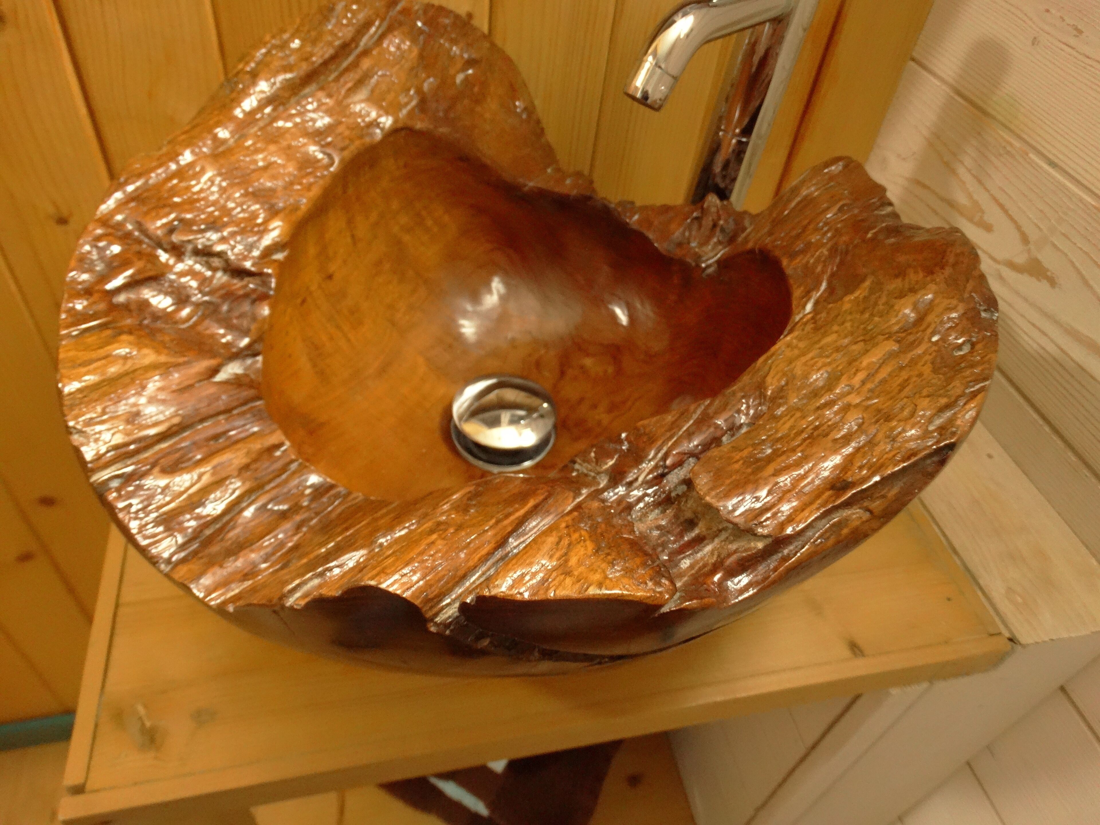 Een houten wastafel met een waskom in de vorm van een hart en een kraan.