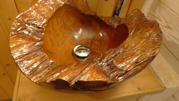 Een houten wastafel met een waskom in de vorm van een hart en een kraan.