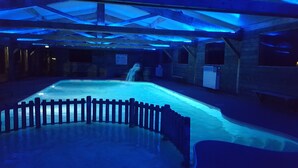 Une piscine intérieure entourée d’une clôture en bois et agrémentée d’une cascade.