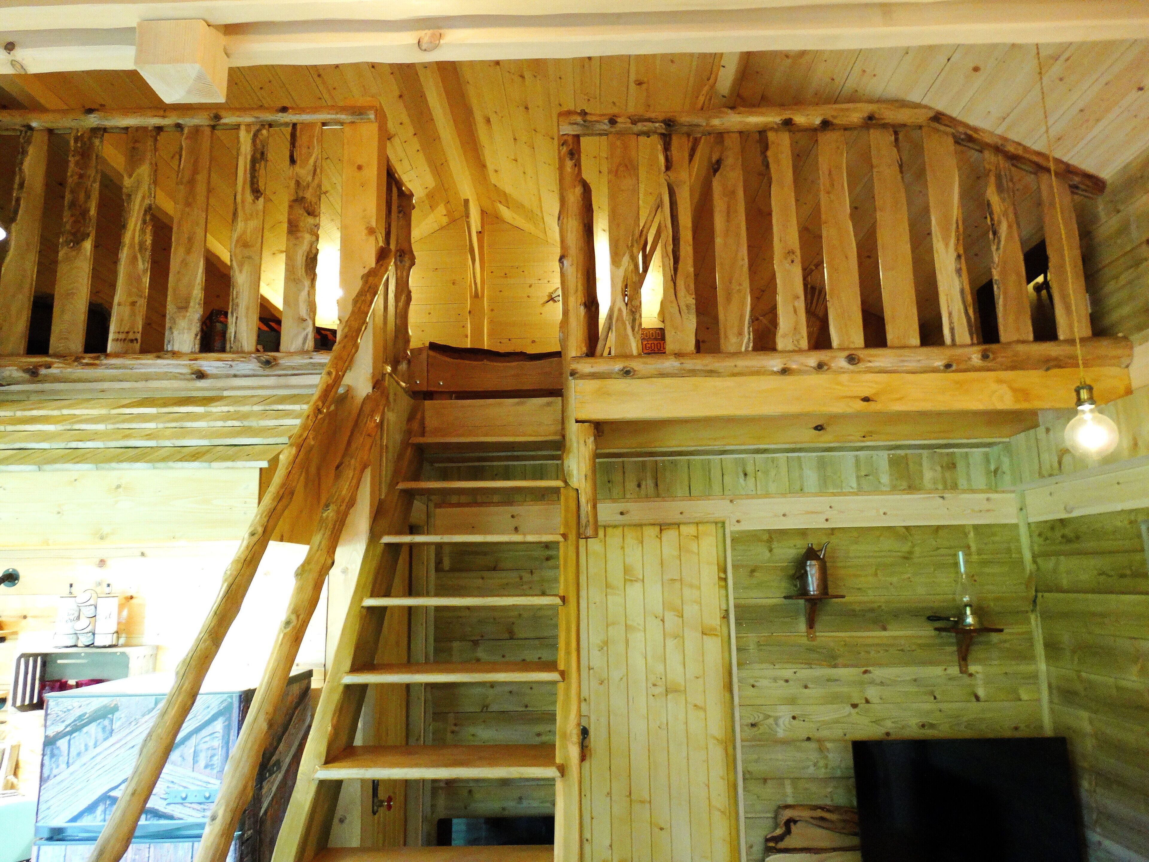 A wooden interior with a staircase leading to a loft area.