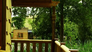 Une terrasse en bois avec une table et des chaises, offrant une vue sur un paysage verdoyant et luxuriant.