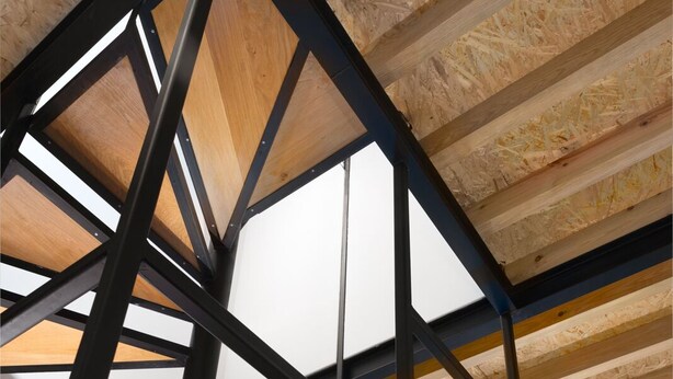 A spiral staircase with exposed wooden beams and black metal railings. - National Theater House 24 (Porto)