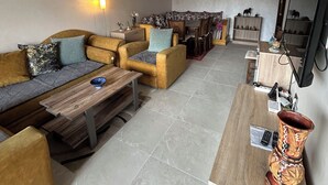Un salon comprenant un canapé, des fauteuils, une table basse, un téléviseur et une cheminée.