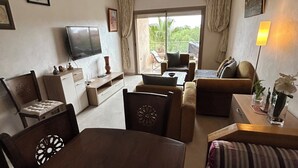 Une chambre d’hôtel comprenant un coin repas, un canapé, une télévision et une vue sur l’extérieur.