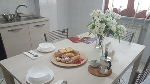 Ein Esstisch mit Tellern, Schüsseln, einer Tasse, einem Löffel, einer Kaffeemaschine und einer Portion Essen.