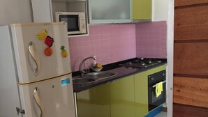 A kitchen with a white refrigerator, a microwave, a stove, and a sink. - Nossa Casa Vossa Casa (Tarrafal)