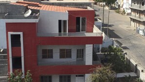A multi-story building with a red and white facade, a flat roof, and satellite dishes. - Nossa Casa Vossa Casa (Tarrafal)