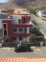 Un edificio de varios pisos con fachada roja y blanca, un techo plano y antenas parabólicas.