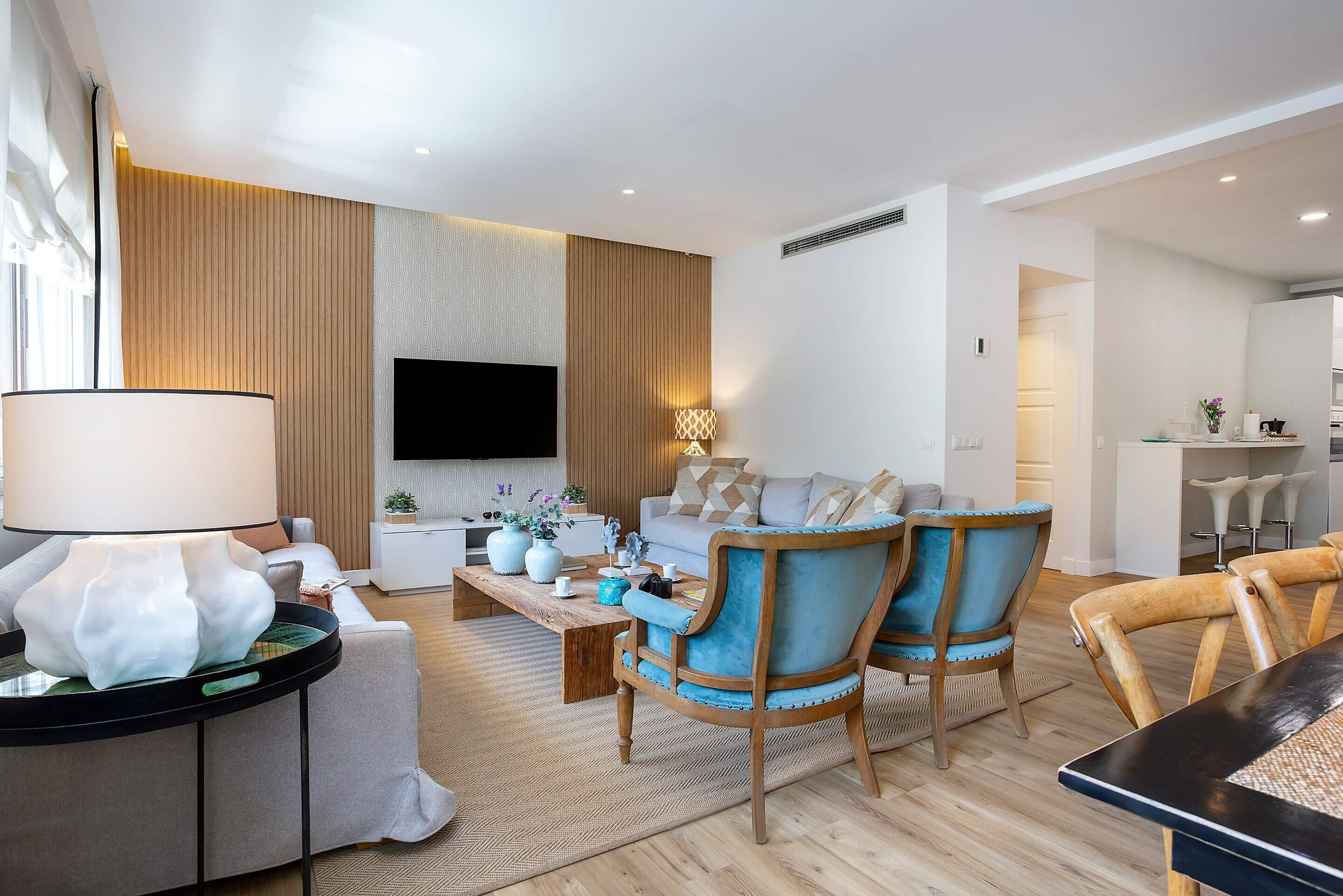 Uma sala de estar moderna com sofá, cadeiras, mesa de centro, televisão e área de jantar.