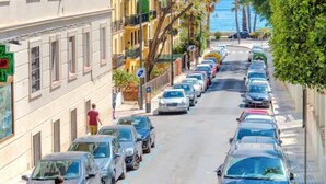 A street lined with parked cars and buildings with balconies.