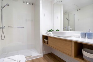Ein modernes Badezimmer mit einer Duschkabine, einem weißen Waschbecken und einem Holzbadezimmermöbel.