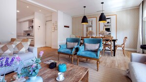 A modern living room with a sofa, two armchairs, a coffee table, and a dining area with a table and chairs.