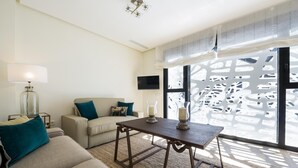 A living room with a sofa, a coffee table, a lamp, and a decorative screen. - Genteel Home Mateos Gago Terrace (Seville)