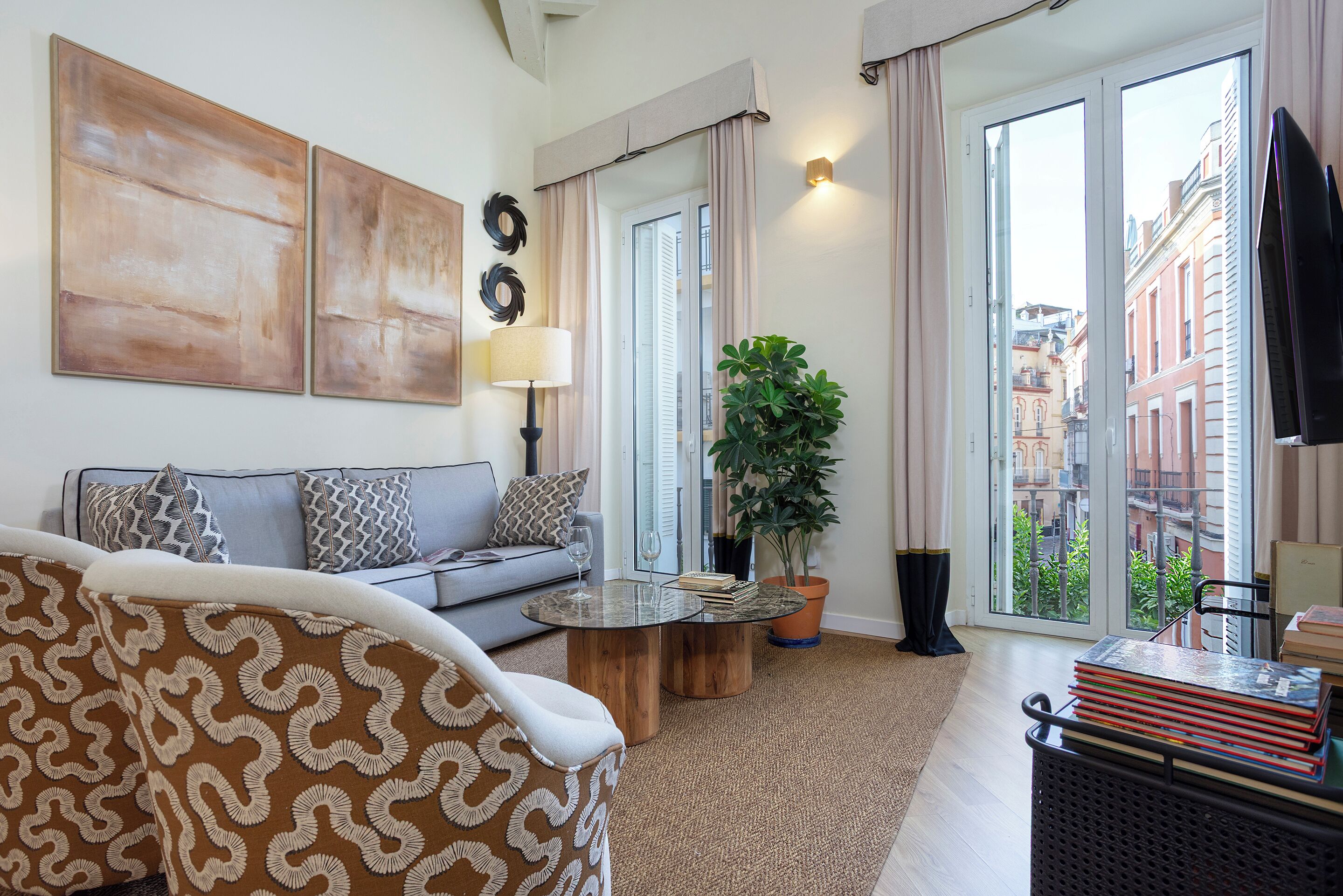 A modern living room with a sofa, coffee table, and a large window with a view of buildings.