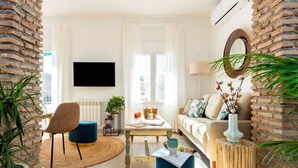 En moderne stue med et fjernsyn, en sofa, et sofabord og en væg i mursten.