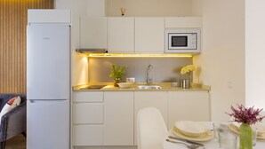 A compact kitchen with white cabinetry, a Bosch refrigerator, a microwave, and a dining area with a table set for two. - Genteel Home Murillo II (Seville)